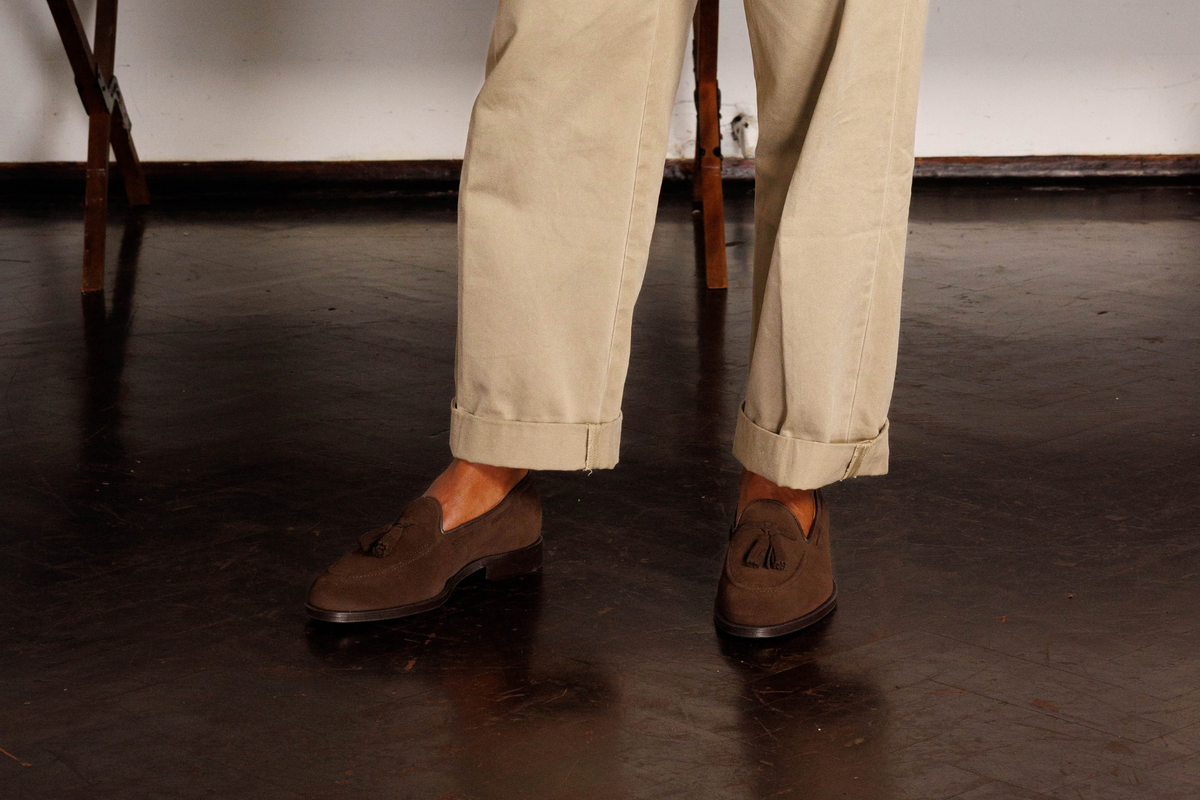 Wildsmith Model 82 tassel loafers in Dark Brown Suede, worn sockless with turned-up stone chinos